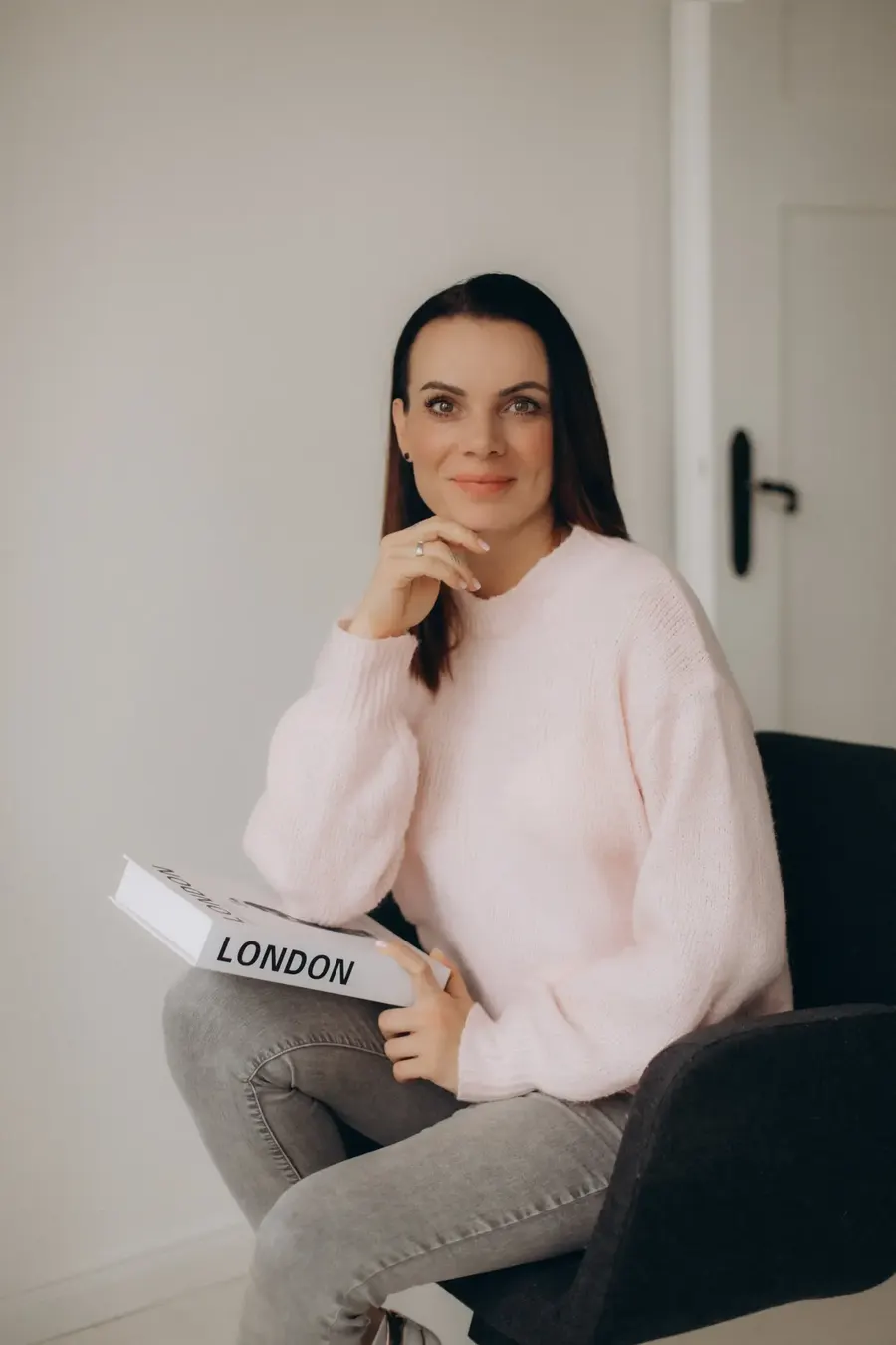 Mandy Schaak sitzt auf einem Stuhl, ein Buch mit der Aufschrift London auf dem Knie